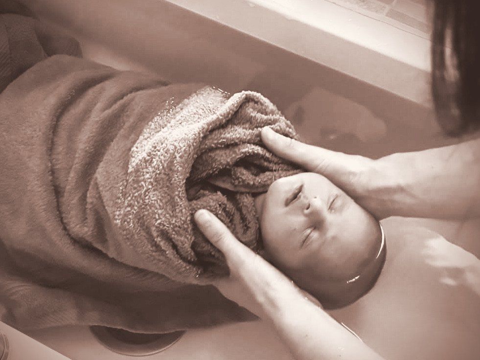 Mains soutenant délicatement la tête d'un bébé endormi dans le bain